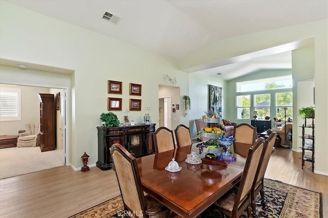 dining area with visible vents, vaulted ceiling, light wood-style flooring, and baseboards