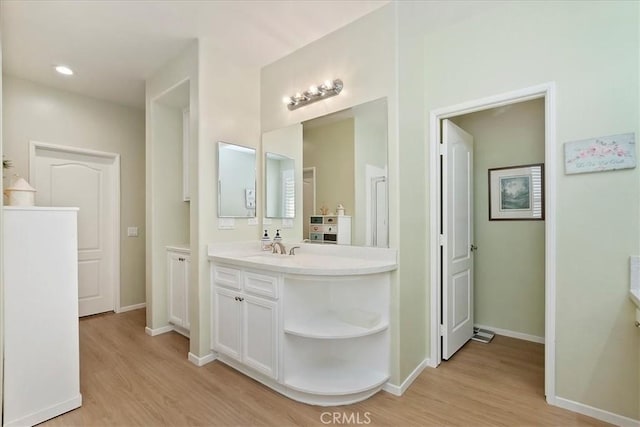 bathroom with recessed lighting, wood finished floors, vanity, and baseboards