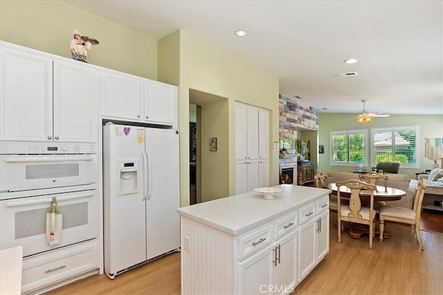 kitchen featuring white appliances, visible vents, white cabinets, open floor plan, and light wood finished floors