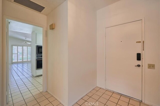 interior space featuring ceiling fan, light tile patterned floors, and vaulted ceiling