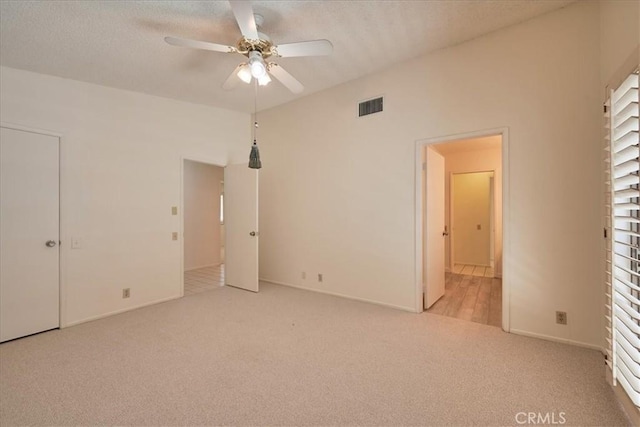 unfurnished bedroom featuring ceiling fan, light colored carpet, ensuite bath, and a textured ceiling