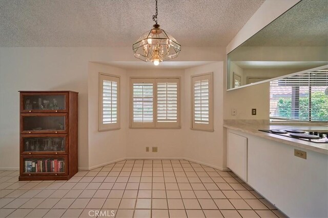 kitchen with pendant lighting, a textured ceiling, electric stovetop, a chandelier, and light tile patterned floors