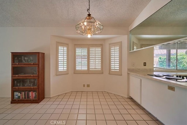 unfurnished dining area with an inviting chandelier, a textured ceiling, and light tile patterned floors