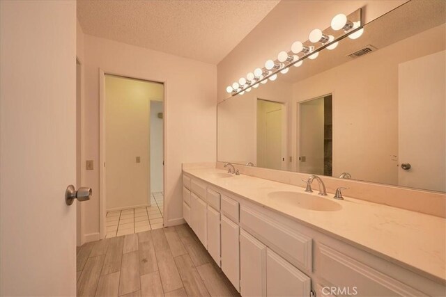 bathroom with vanity, hardwood / wood-style floors, and a textured ceiling