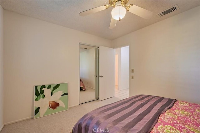 bedroom with light carpet, ceiling fan, and a textured ceiling