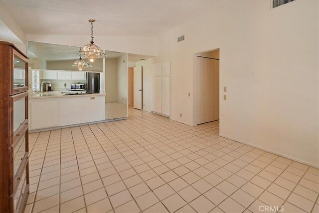 kitchen featuring appliances with stainless steel finishes, pendant lighting, lofted ceiling, sink, and white cabinets