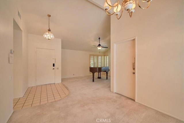 entrance foyer with ceiling fan with notable chandelier, carpet floors, and vaulted ceiling