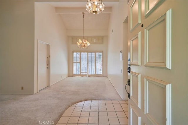 carpeted foyer entrance featuring high vaulted ceiling, beamed ceiling, and an inviting chandelier