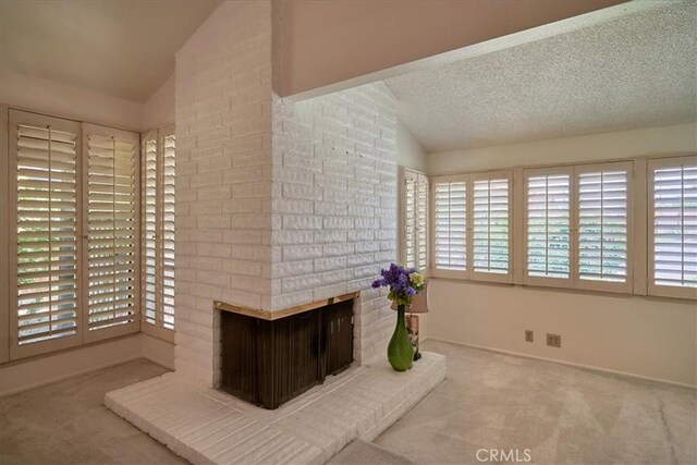 interior space featuring lofted ceiling, a fireplace, and light colored carpet