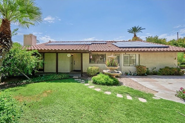 back of property with a yard and solar panels