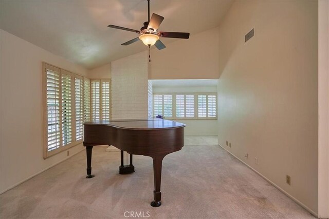 sitting room with high vaulted ceiling, light colored carpet, and ceiling fan