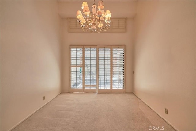 carpeted empty room with a notable chandelier