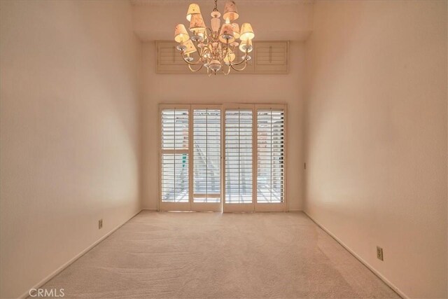 carpeted spare room featuring an inviting chandelier