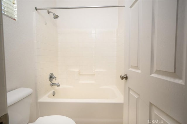 bathroom featuring tiled shower / bath combo and toilet