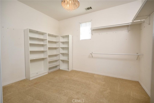 spacious closet with light carpet and a chandelier