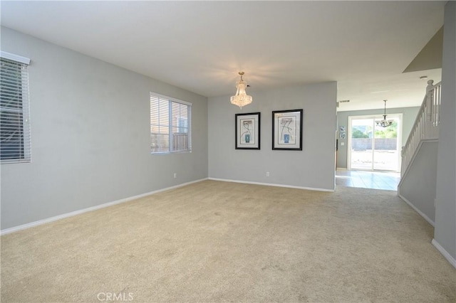 carpeted empty room with an inviting chandelier