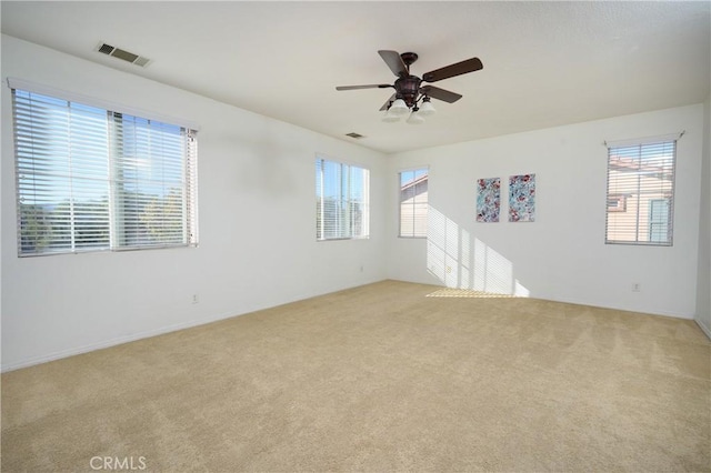 unfurnished room featuring light colored carpet, plenty of natural light, and ceiling fan