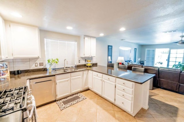 kitchen featuring tasteful backsplash, sink, kitchen peninsula, white cabinetry, and appliances with stainless steel finishes