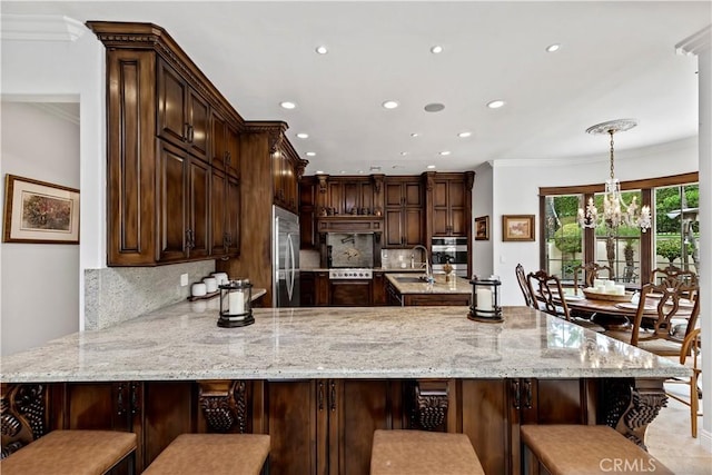 kitchen with appliances with stainless steel finishes, pendant lighting, a breakfast bar area, and kitchen peninsula