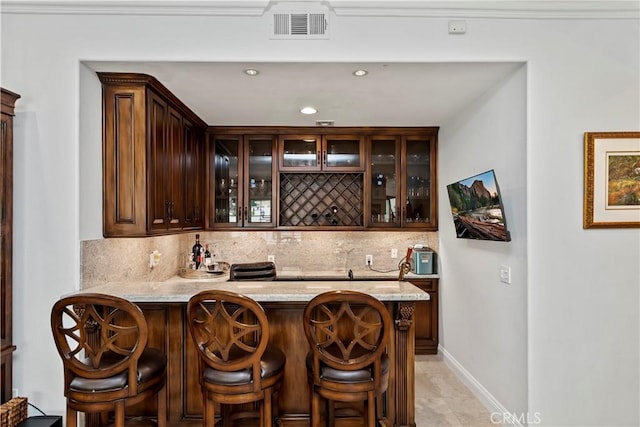 bar featuring dark brown cabinetry, light tile patterned floors, backsplash, and light stone counters