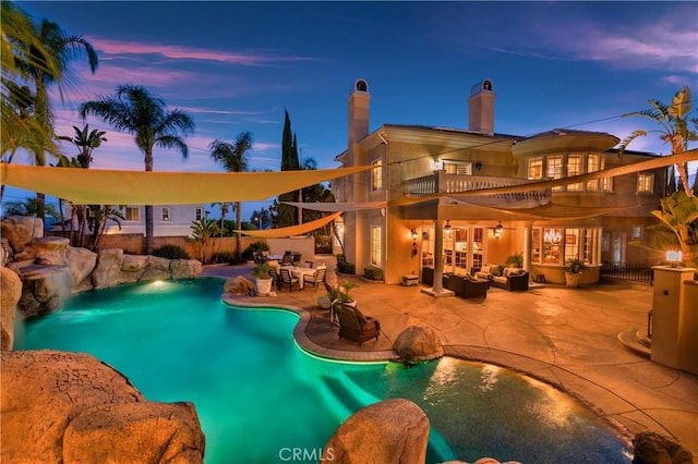 pool at dusk with an outdoor living space and a patio area