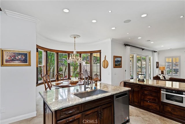 kitchen featuring sink, stainless steel appliances, ornamental molding, a center island with sink, and decorative light fixtures