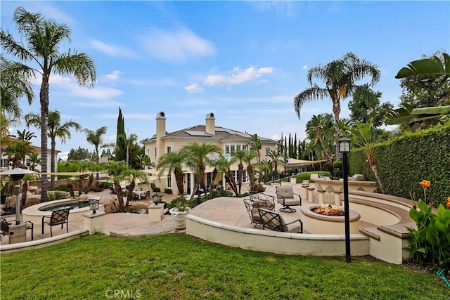 view of home's community featuring a patio area, a fire pit, and a lawn