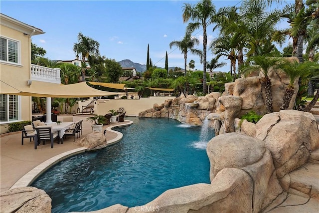 view of swimming pool featuring pool water feature, a mountain view, and a patio area