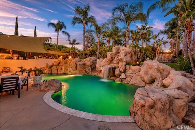 pool at dusk featuring a patio