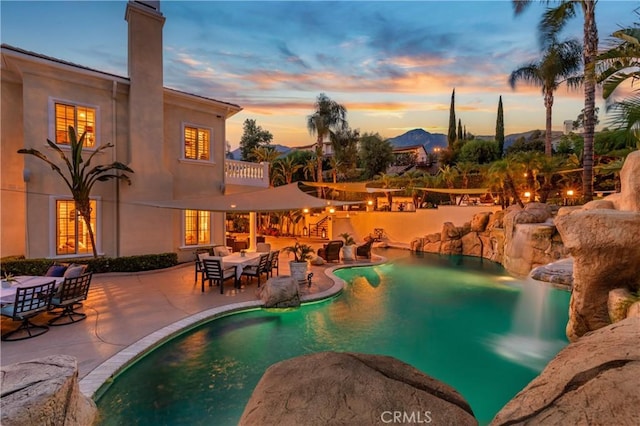 pool at dusk with a patio area