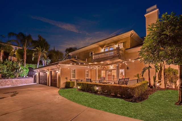 view of front of property featuring a garage, a balcony, and a yard