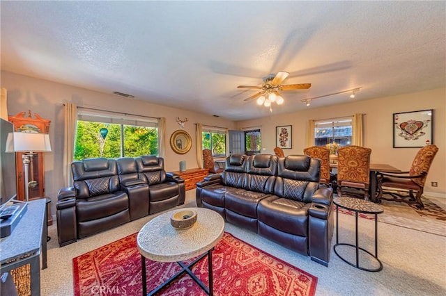 carpeted living room featuring ceiling fan and a textured ceiling