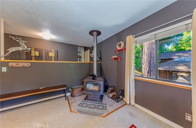 recreation room featuring a wood stove, carpet floors, and a textured ceiling