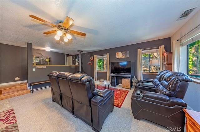 living room featuring ceiling fan, light colored carpet, and a textured ceiling