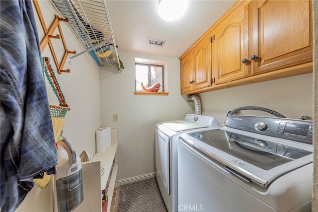 washroom featuring washer and dryer, a textured ceiling, and cabinets