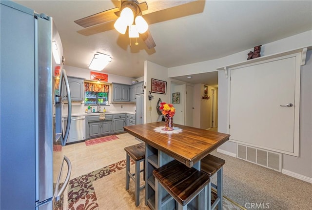 tiled dining room with ceiling fan and sink