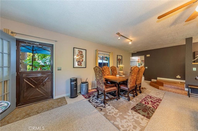 carpeted dining space featuring a textured ceiling, rail lighting, and ceiling fan