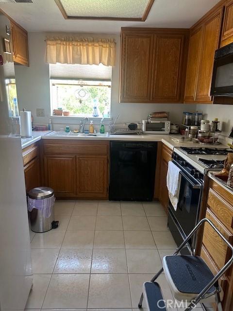 kitchen featuring light tile patterned floors, sink, and black appliances