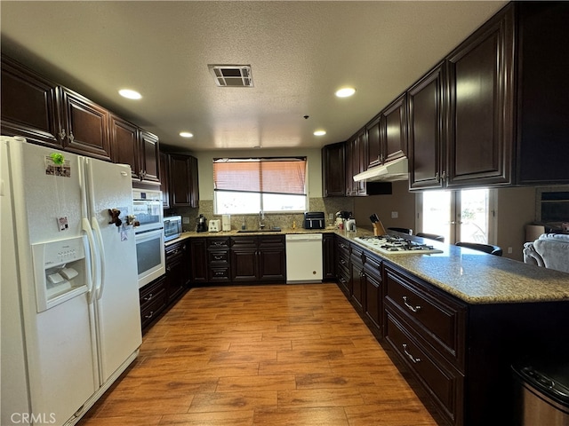 kitchen featuring sink, kitchen peninsula, a textured ceiling, appliances with stainless steel finishes, and light wood-type flooring