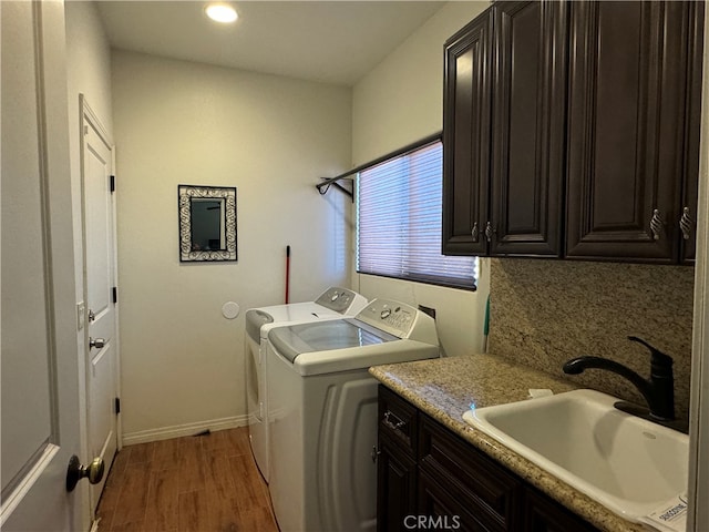 laundry area featuring cabinets, wood-type flooring, washer and dryer, and sink