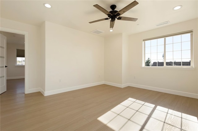 unfurnished room featuring visible vents, light wood-style flooring, and a healthy amount of sunlight