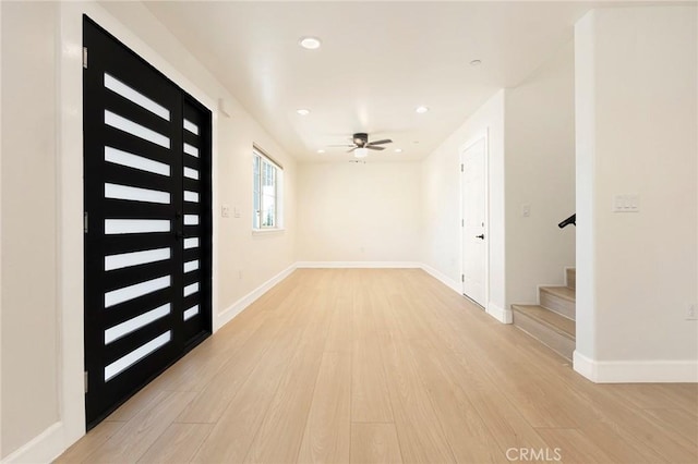 foyer with stairs, light wood-style floors, and baseboards