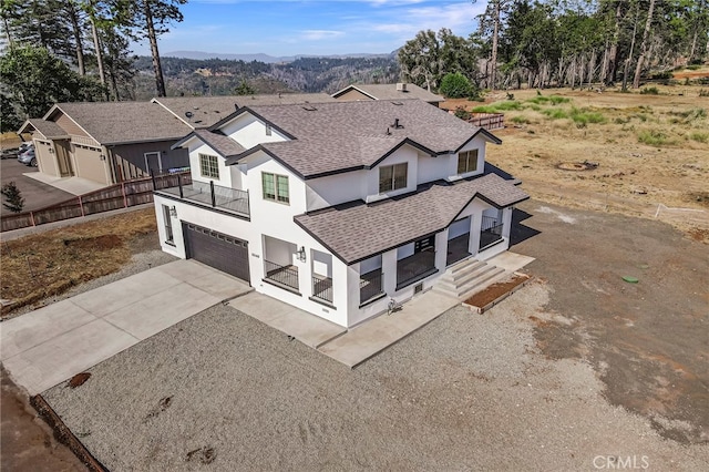 view of front of house featuring concrete driveway, roof with shingles, a garage, a balcony, and a mountain view