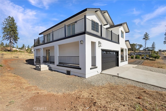 view of property exterior featuring stucco siding, a balcony, and driveway