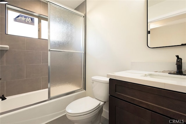 full bathroom featuring vanity, toilet, and shower / bath combination with glass door