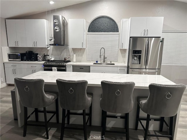 kitchen featuring exhaust hood, stainless steel appliances, a center island, and sink