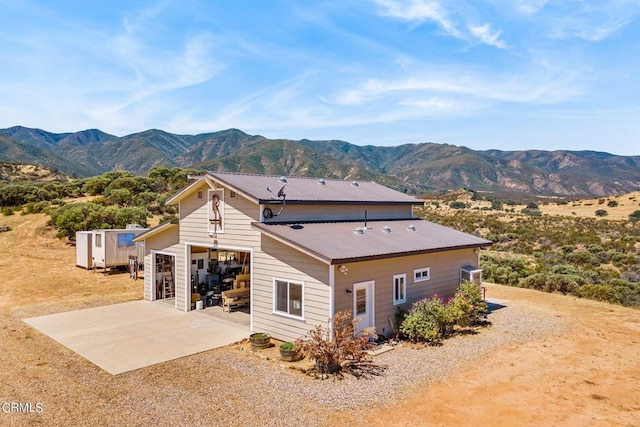 rear view of property with a patio, a storage unit, and a mountain view