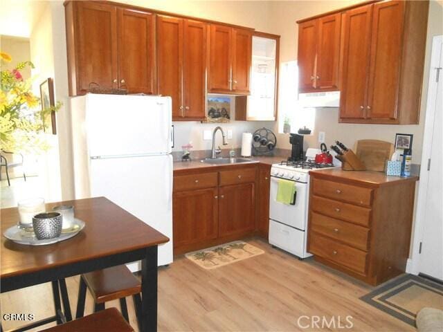 kitchen with sink, white appliances, and light wood-type flooring