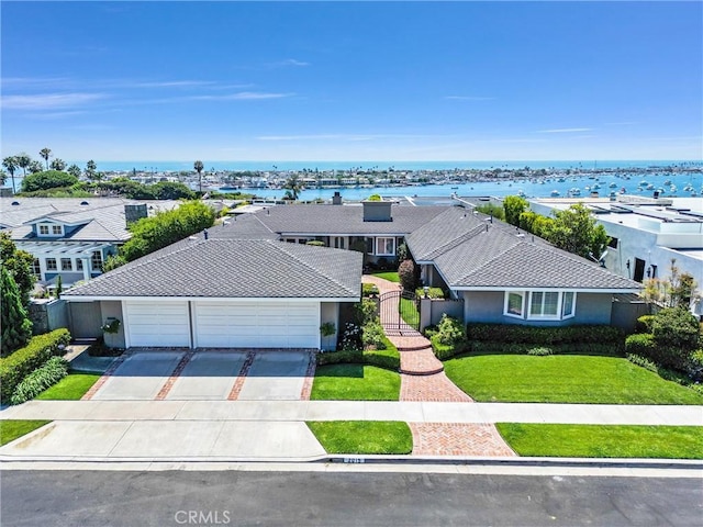 view of front of property with a front yard, a water view, and a garage