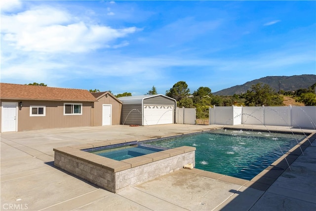 view of pool featuring a mountain view, a patio area, pool water feature, an in ground hot tub, and an outdoor structure